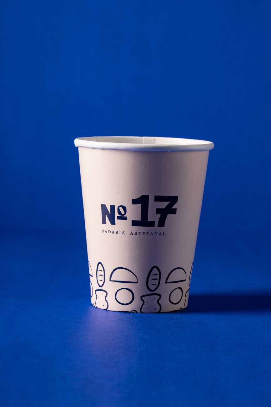 Copo de papel personalizado com a marca Nº 17 Padaria Artesanal sobre fundo azul